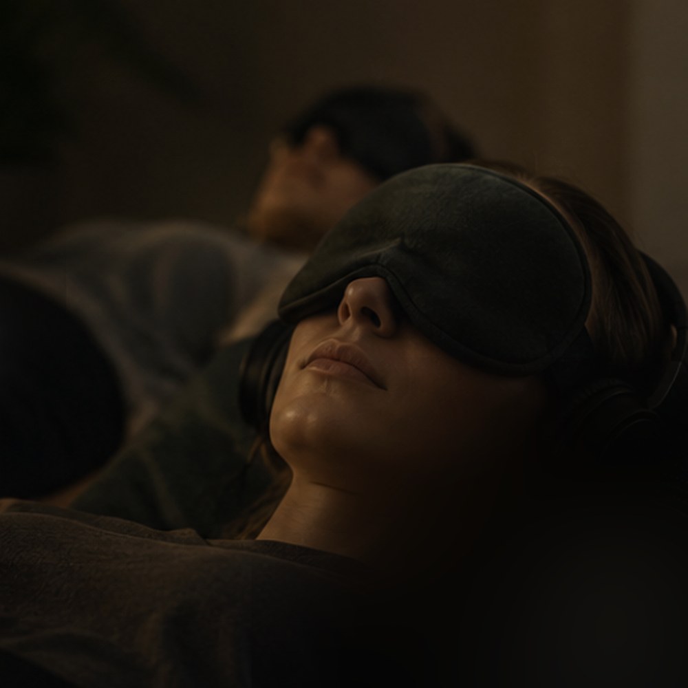 A 9D Breathwork participant lying down wearing an eye mask and headphones